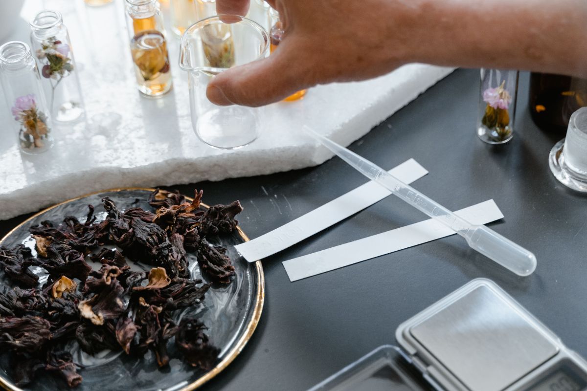 Formulator weighing botanical ingredients at the lab bench for cosmetic formulation