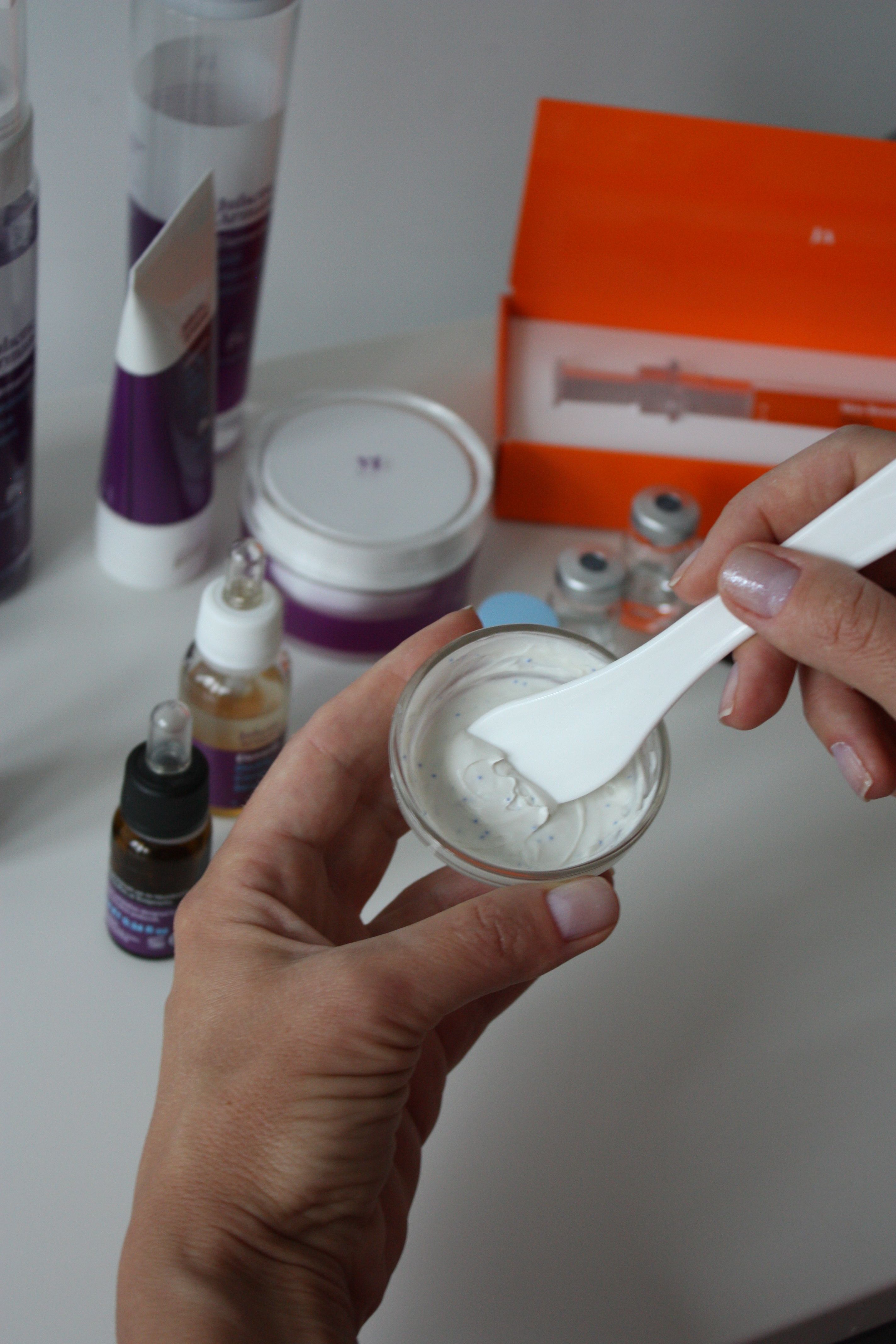 Cream being mixed with a spatula in a small glass lab beaker for cosmetic manufacturing