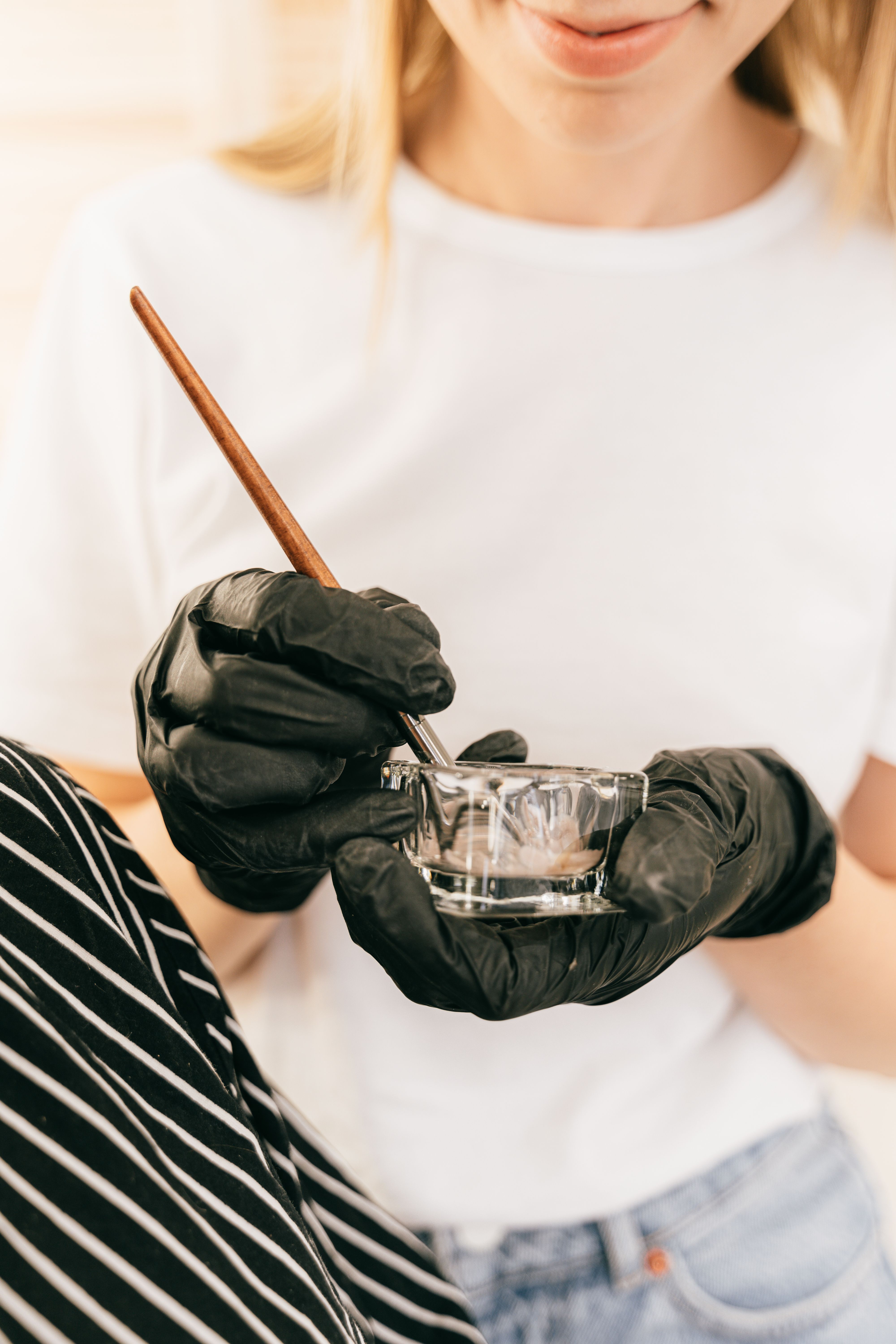 Gloved hands mixing a formula in a glass bowl skincare manufacturing