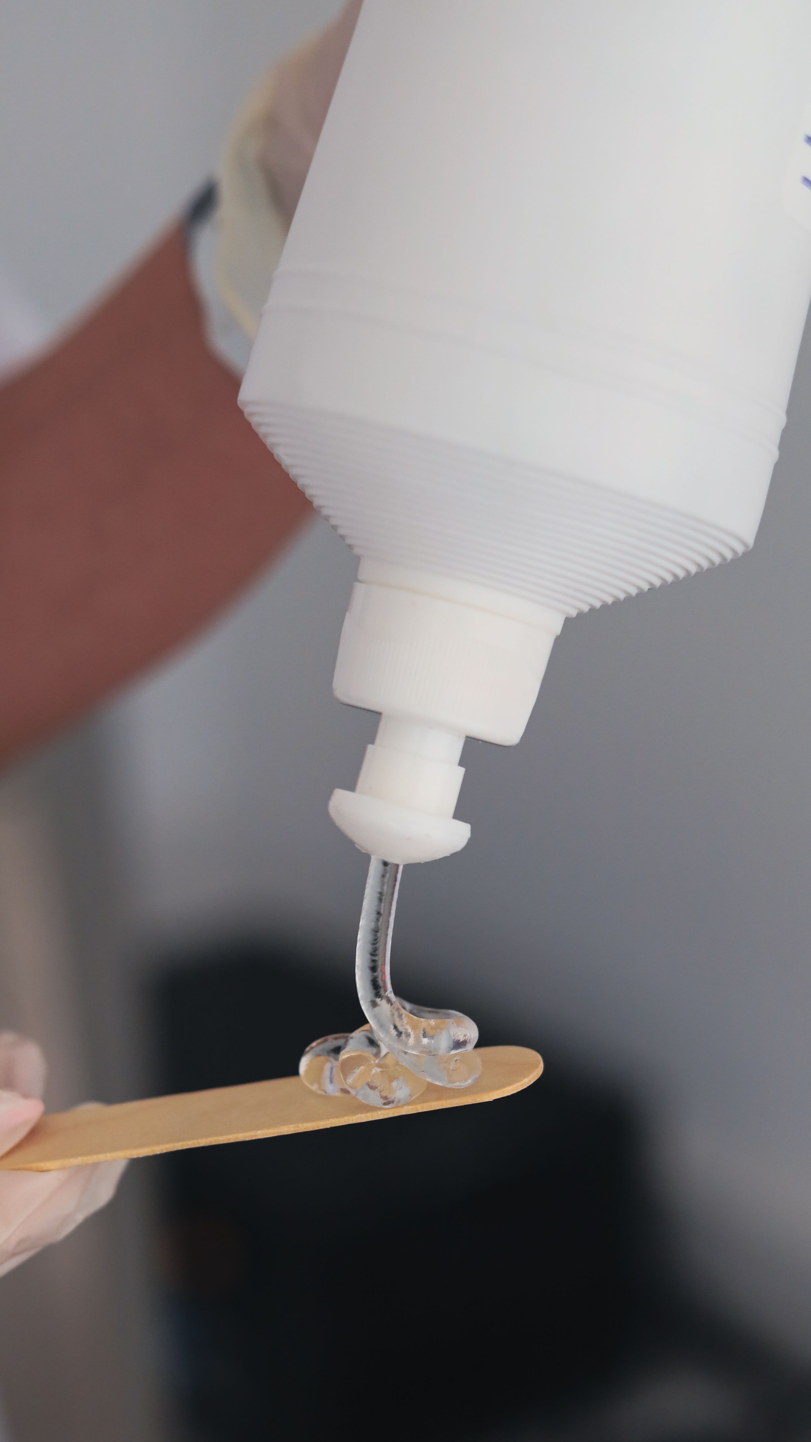 Thick clear gel dispensed from a pump bottle onto a spatula skincare manufacturing